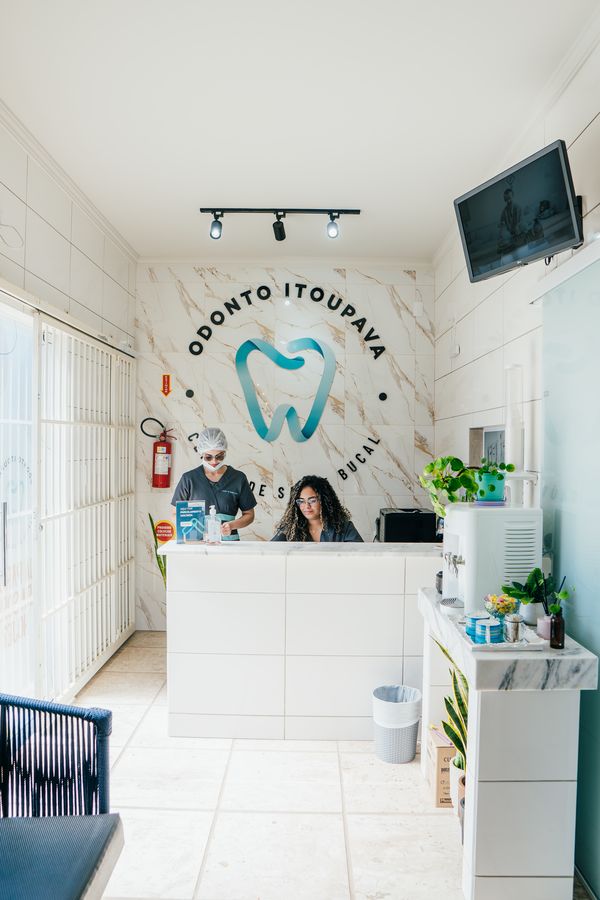 Recepção da clínica, com a logo da Odonto Itoupava na parede de mármore